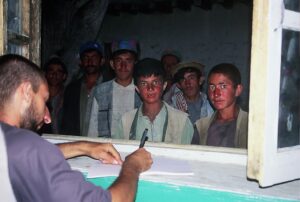 Didier écrivant en Afghanistan devant les villageois